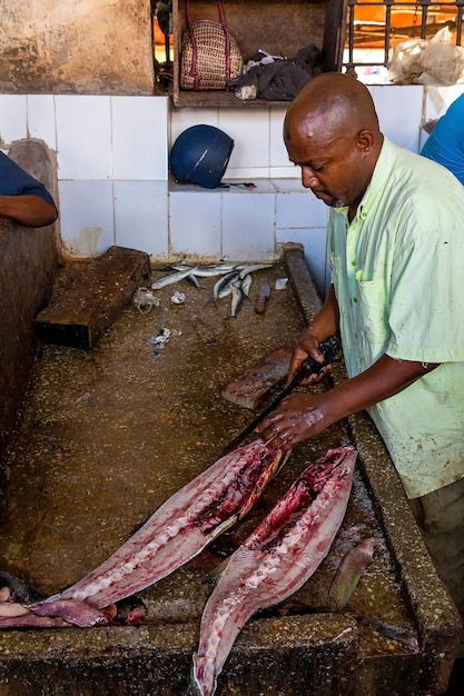 Un hombre limpia pescado fresco en el mercado de Stone Town, Zanzíbar. Tanzania