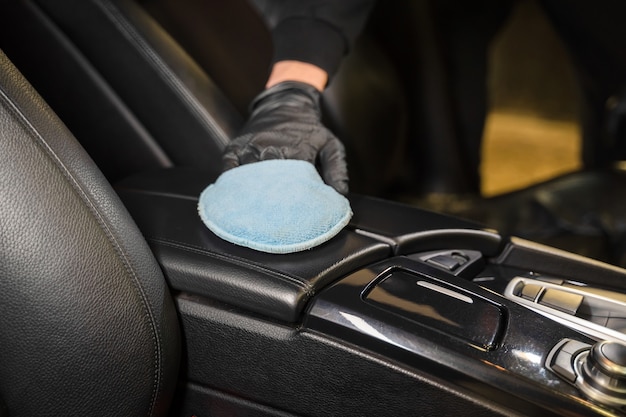 El hombre limpia el reposabrazos de cuero del coche.