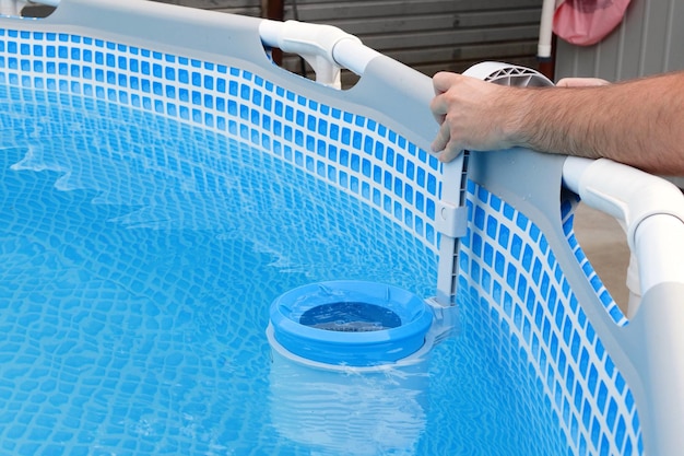 El hombre limpia el skimmer para la piscina de marco Concepto de limpieza de piscinas contaminadas