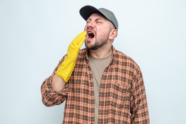 Hombre limpiador eslavo disgustado con guantes de goma manteniendo la mano cerca de la boca