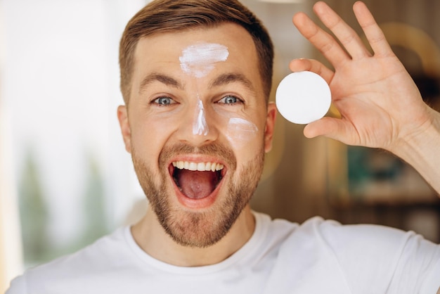 Hombre limpiando la cara con una esponja en casa