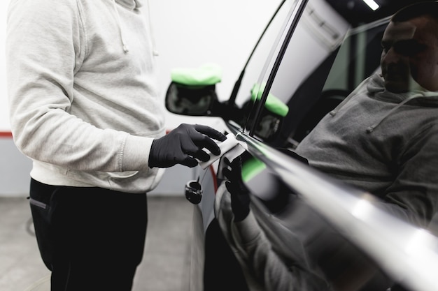 Un hombre limpiando un coche, un coche que detalla el concepto (o valet). Enfoque selectivo.