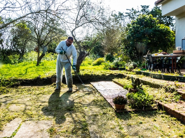 Hombre limpiando con escoba de hierro en el jardín