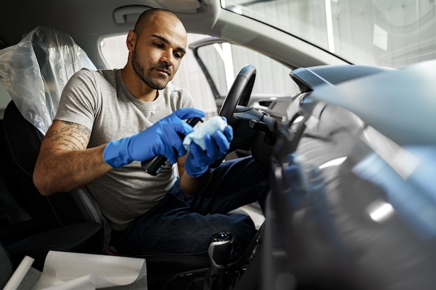 Un hombre limpiando el interior del coche, detallando el coche en el servicio de lavado de coches, de cerca