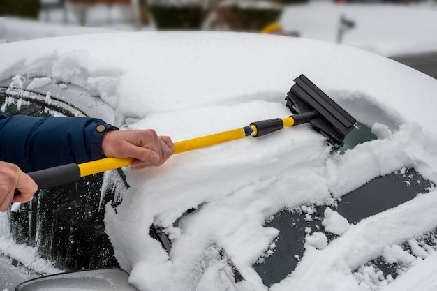 Hombre limpiando la nieve de su coche durante las nevadas invernales