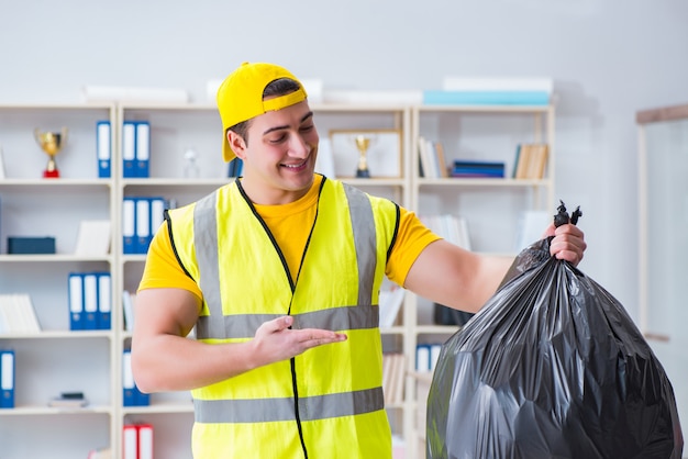 Hombre limpiando la oficina y sosteniendo la bolsa de basura