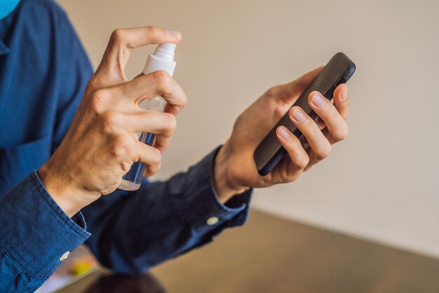 Hombre limpiando la pantalla del teléfono inteligente con alcohol o desinfectante Concepto de limpieza del teléfono de pantalla sucia para la prevención de enfermedades por bacterias coronavirus covid 19