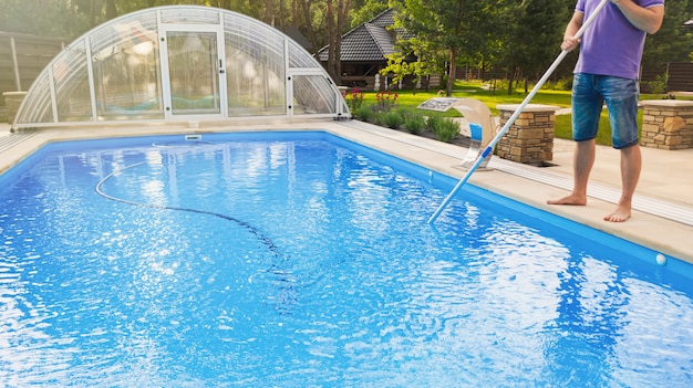 Foto hombre limpiando la piscina con un aspirador de tubos temprano