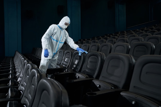 Foto hombre limpiando sillas trapo en la sala de cine