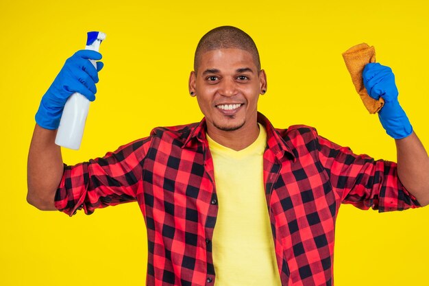 Hombre de limpieza brasileño latino con guantes de cinta en el fondo amarillo del estudio.