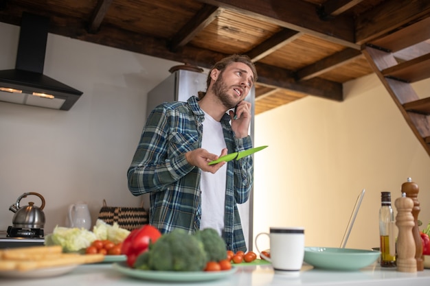 Foto un hombre llama a su novia para preguntarle sobre la receta.