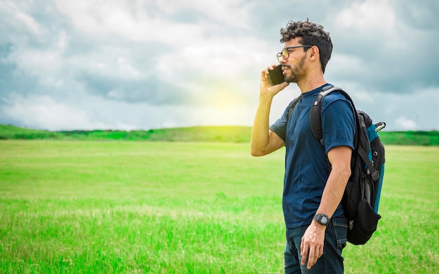 Hombre llamando por celular joven en el campo llamando por celular