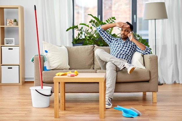 Foto hombre llamando por teléfono inteligente después de limpiar la casa