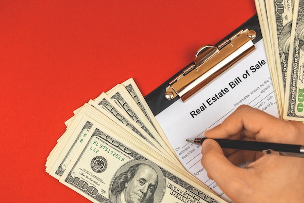 Hombre llenando el contrato de venta de bienes raíces. Firma del concepto de contrato. Mesa de oficina con dinero