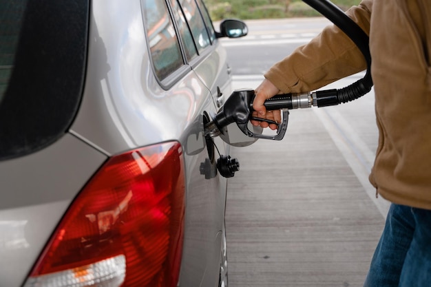 hombre llenando el tanque de combustible del coche con combustible diesel en la gasolinera cerca como el costo del combustible subiendo