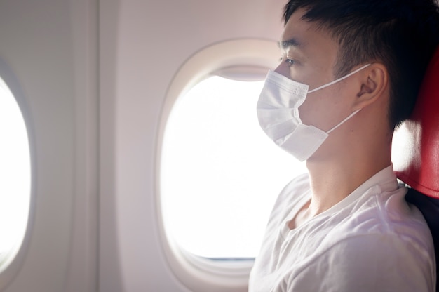 Foto el hombre lleva una máscara protectora a bordo del avión, viaja bajo la pandemia de covid-19