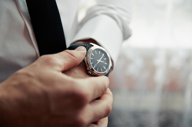 Un hombre lleva un reloj y lo está mirando.