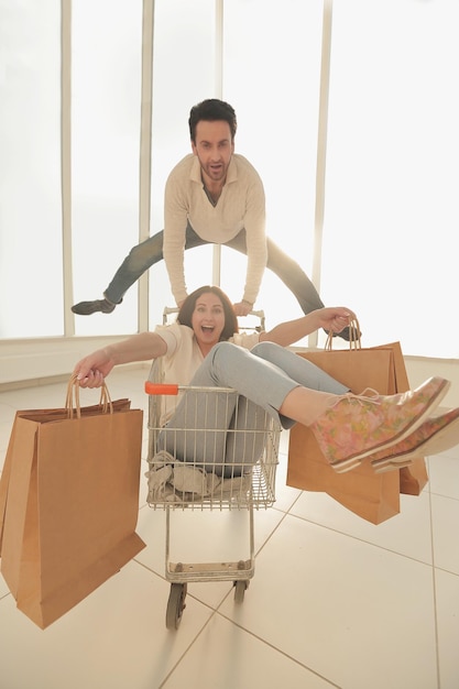 Foto el hombre lleva a su novia en una foto de carrito de compras con espacio de copia