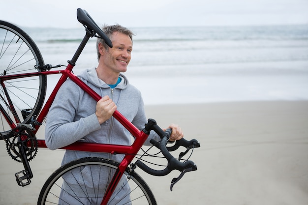 Hombre llevando bicicleta en la playa