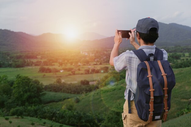 Hombre llevando una bolsa y usando un teléfono para tomar fotos