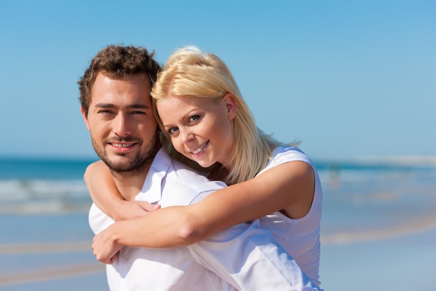 hombre llevando a su chica en la playa