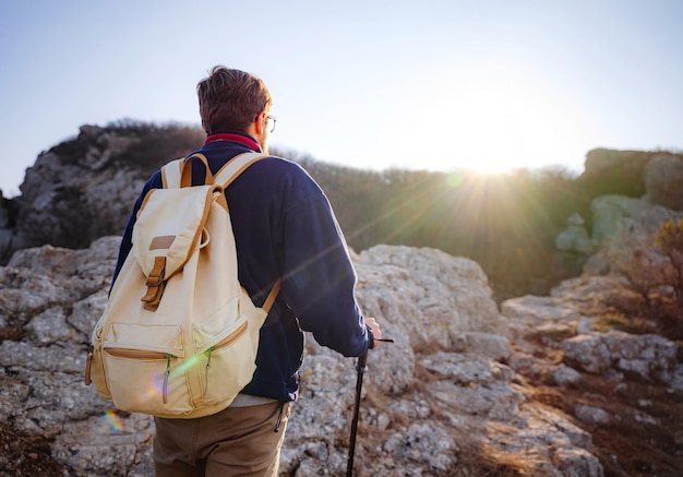 Un hombre en lo alto de un acantilado en las montañas de primavera al atardecer y disfrutando de la vista de la naturaleza