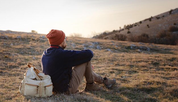 Un hombre en lo alto de un acantilado en las montañas de primavera al atardecer y disfrutando de la vista de la naturaleza