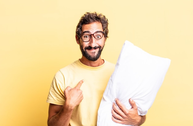 Hombre loco expresivo que se siente feliz y apuntando a sí mismo con un emocionado y sosteniendo una almohada