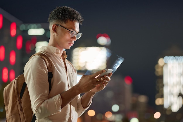 Hombre de luces nocturnas de la ciudad con tecnología telefónica y comunicación futurista en línea con bokeh Vida urbana en las redes sociales y joven hipster escribiendo en un teléfono inteligente con conexión 5g en una aplicación digital en línea