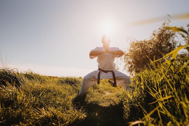 Un hombre luchador de karate en kimono blanco entrenando al aire libre en el parque