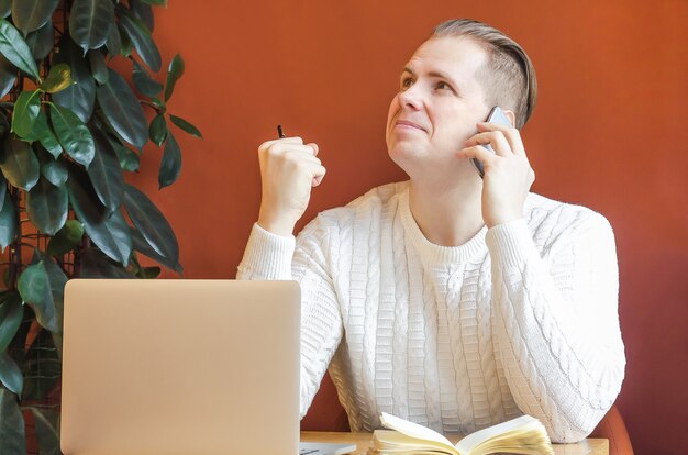 Hombre en el lugar de trabajo con la computadora hablando por teléfono