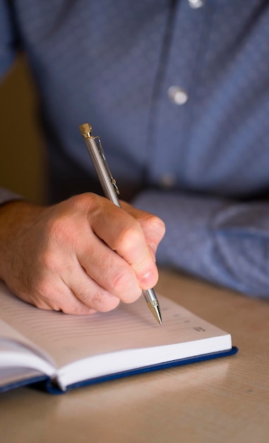 Hombre en el lugar de trabajo tomando notas con un bolígrafo en una imagen de cuaderno con enfoque selectivo