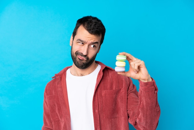 Foto hombre con macarons sobre pared aislada