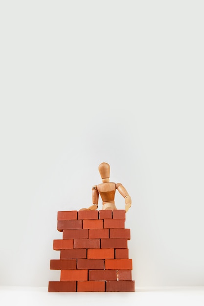 Un hombre de madera construye una pared de ladrillos a su alrededor.