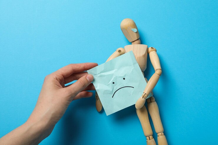 Hombre de madera y papel en mano femenina sobre fondo azul vista superior