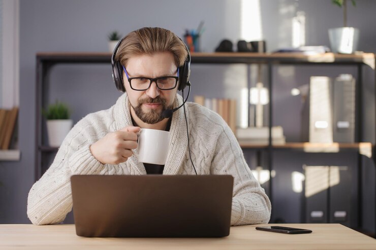 Hombre maduro en auriculares usando una computadora portátil en casa