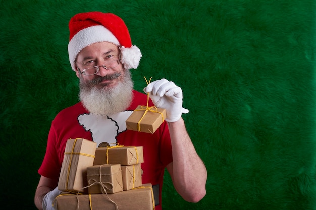 Foto hombre maduro con barba vistiendo gorro de papá noel con muchos regalos en la mano