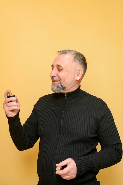 Foto hombre maduro con una botella de perfume