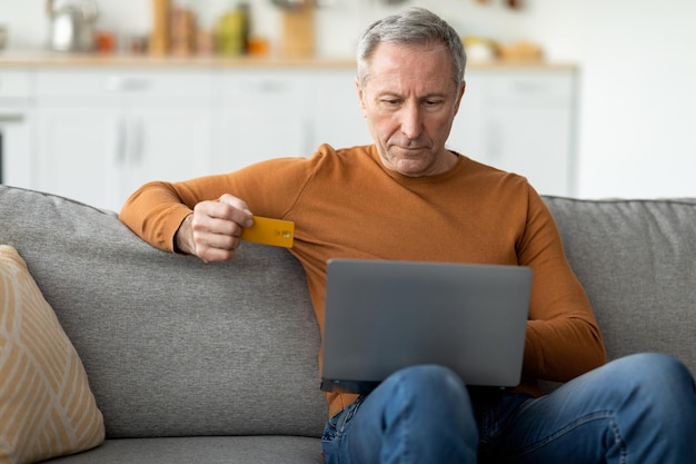 Hombre maduro casual usando pc y tarjeta de crédito en casa