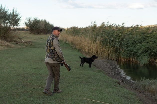 Hombre maduro cazador con arma mientras camina en el campo con sus perros