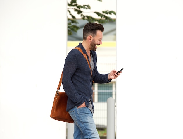 Hombre maduro feliz en la calle de la ciudad con teléfono celular