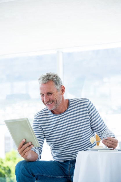 Hombre maduro feliz que sostiene la tableta digital