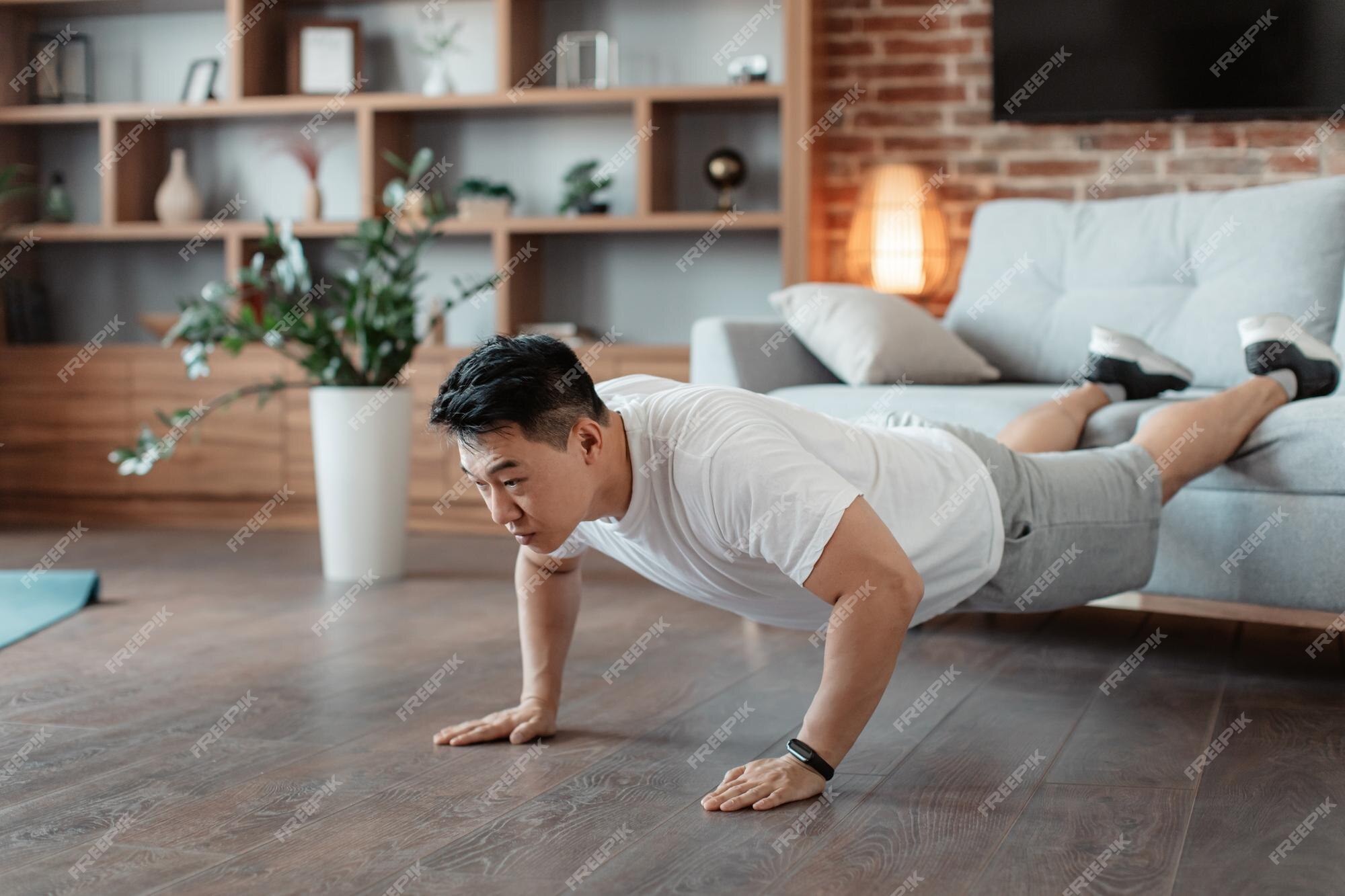 Hombre maduro fuerte haciendo flexiones con las piernas en el sofá haciendo  ejercicio en casa ejercitando las manos y los músculos abdominales | Foto  Premium
