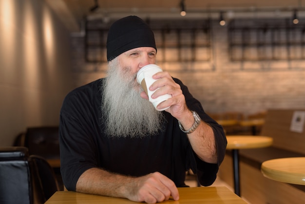 Hombre maduro guapo barba hipster tomando café en la cafetería.