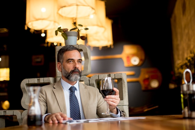 Hombre maduro guapo vaso de vino tinto en el restaurante