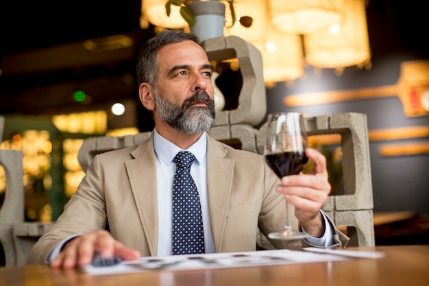 Hombre maduro guapo vaso de vino tinto en el restaurante