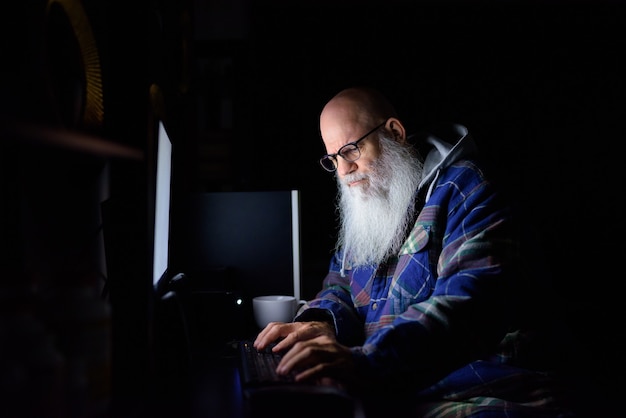 Hombre maduro hipster barbudo Calvo trabajando horas extras en casa por la noche