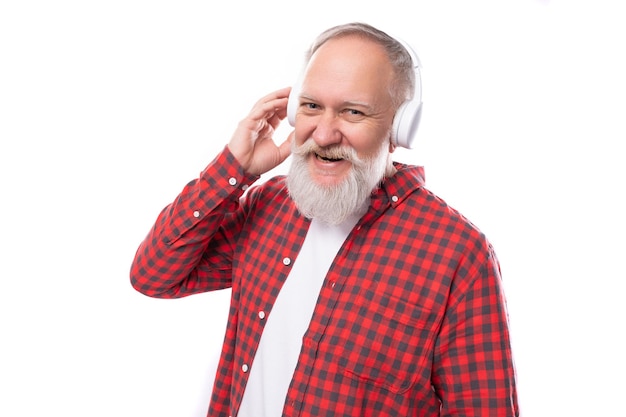 Un hombre maduro de mediana edad amante de la música moderna con una camisa elegante escucha música nueva en los auriculares