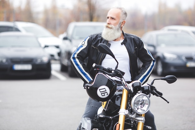 Hombre maduro montando una motocicleta. Viejo macho en moto. Hombre barbudo conduciendo al aire libre.