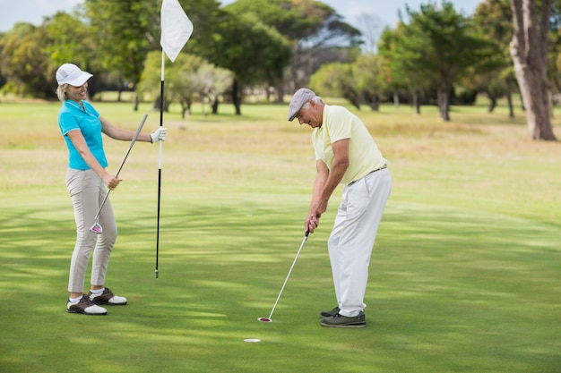 Hombre maduro y mujer jugando al golf